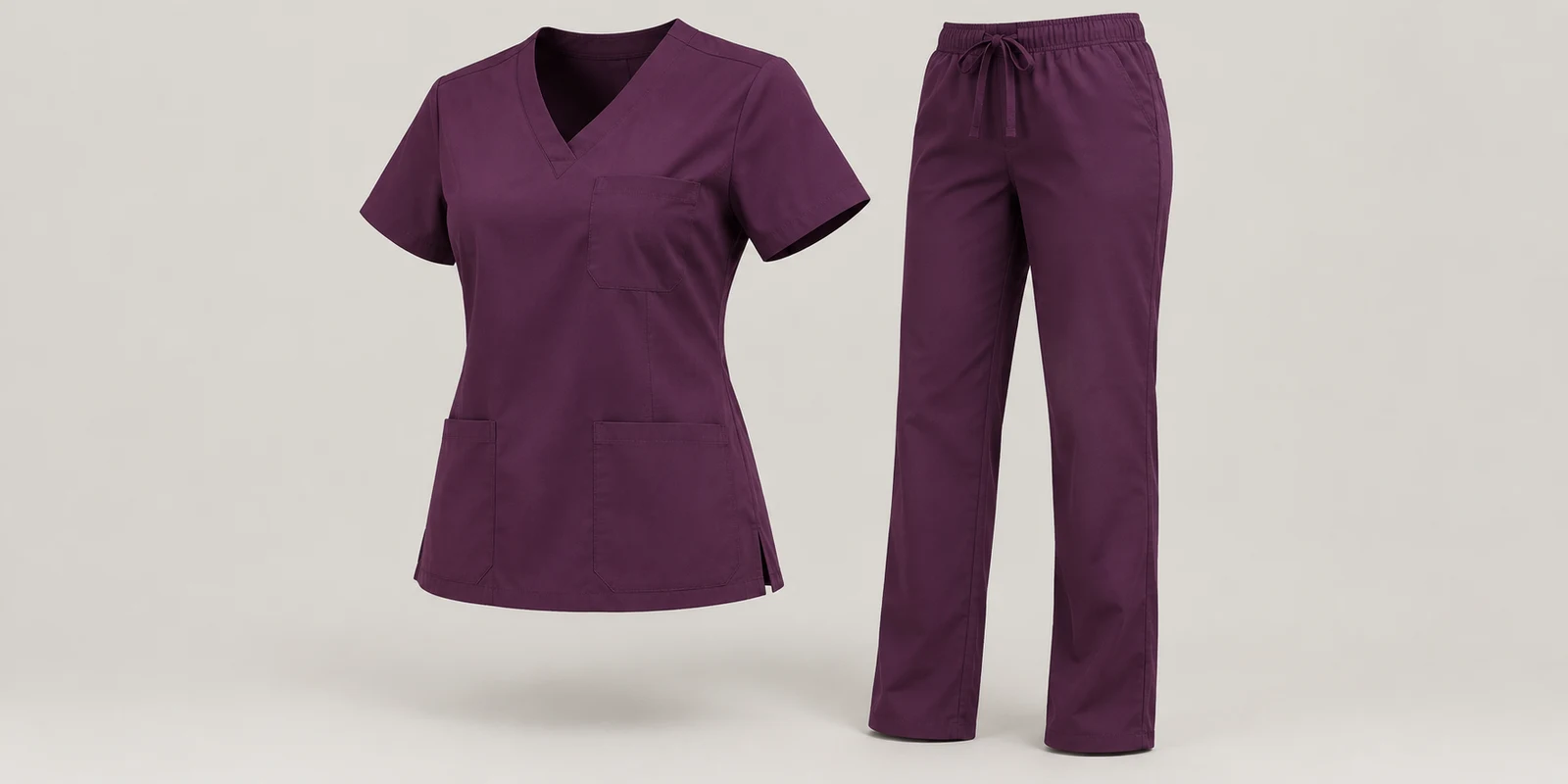 Illustrative plum medical scrub set showing shoulder shape and trouser proportions on warm-grey background