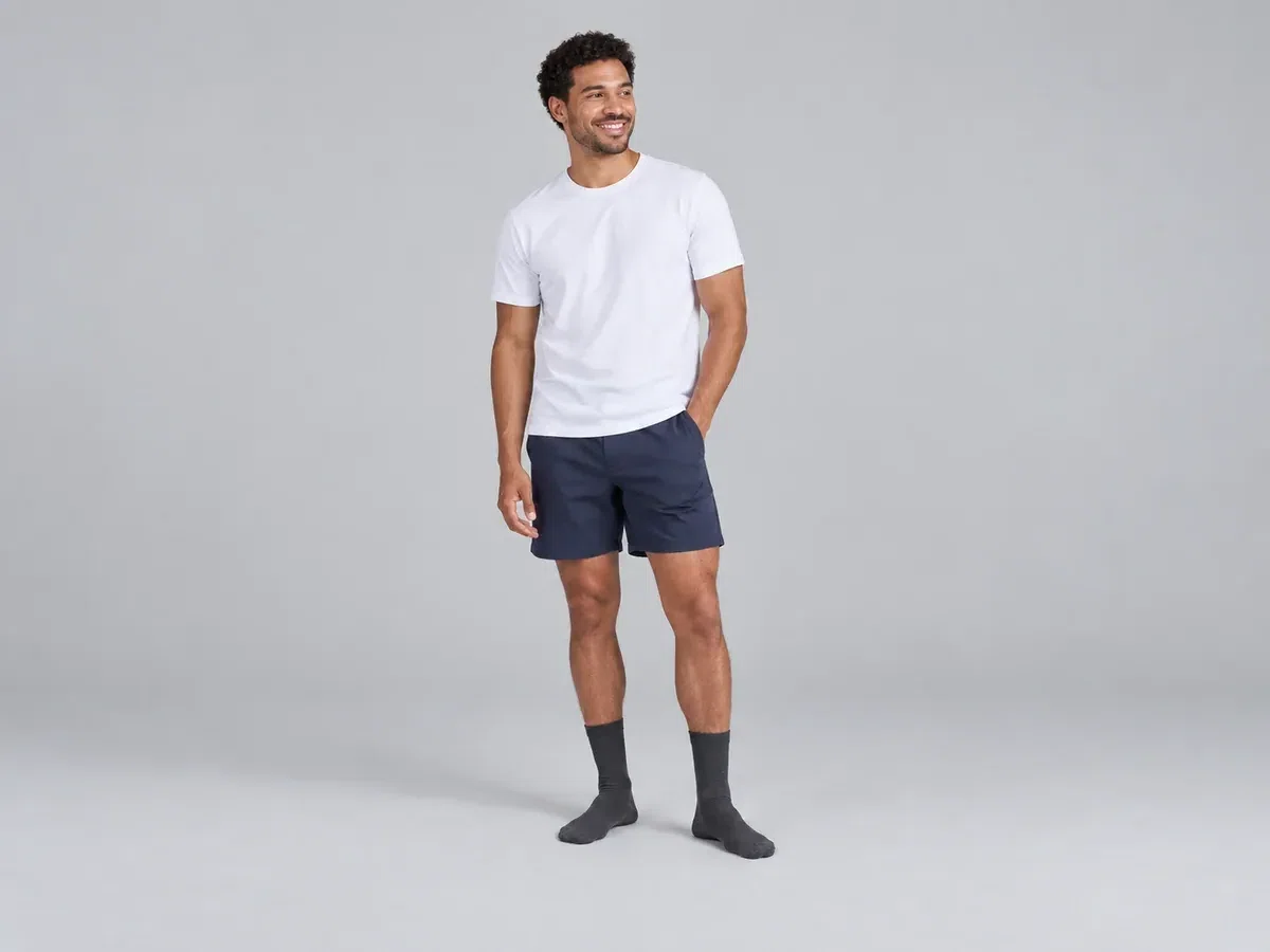 Man wearing dark socks and navy shorts against a plain grey background